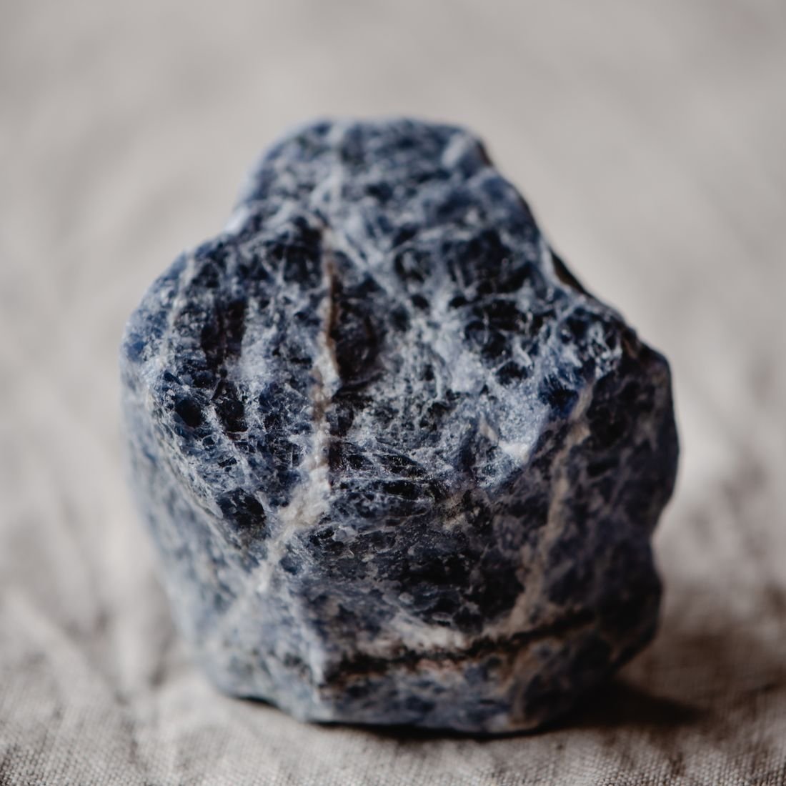 A rough blue sodalite crystal with white calcite veining