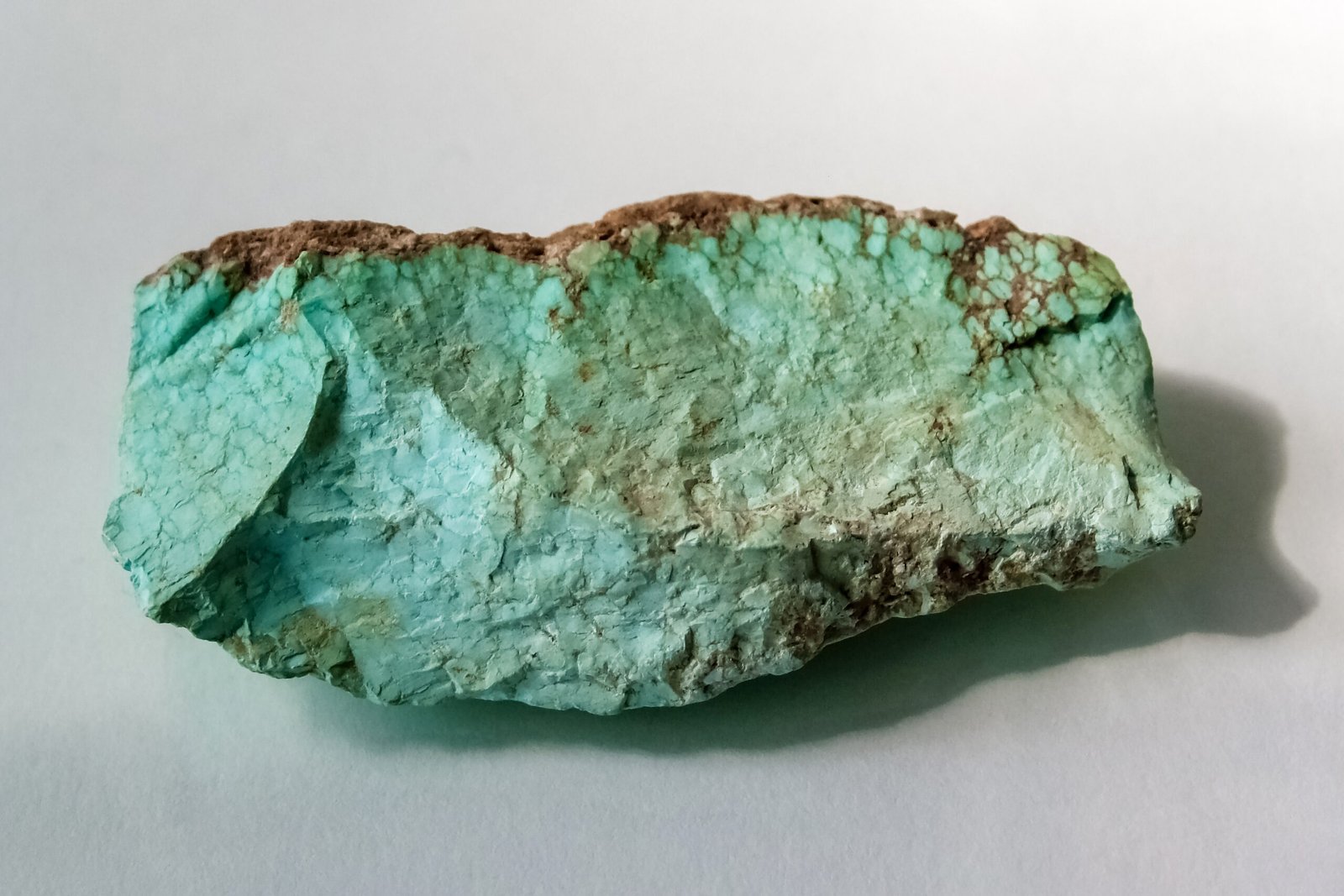 Rough natural turquoise from Arizona, sky-blue with dark brown host-rock matrix veining
