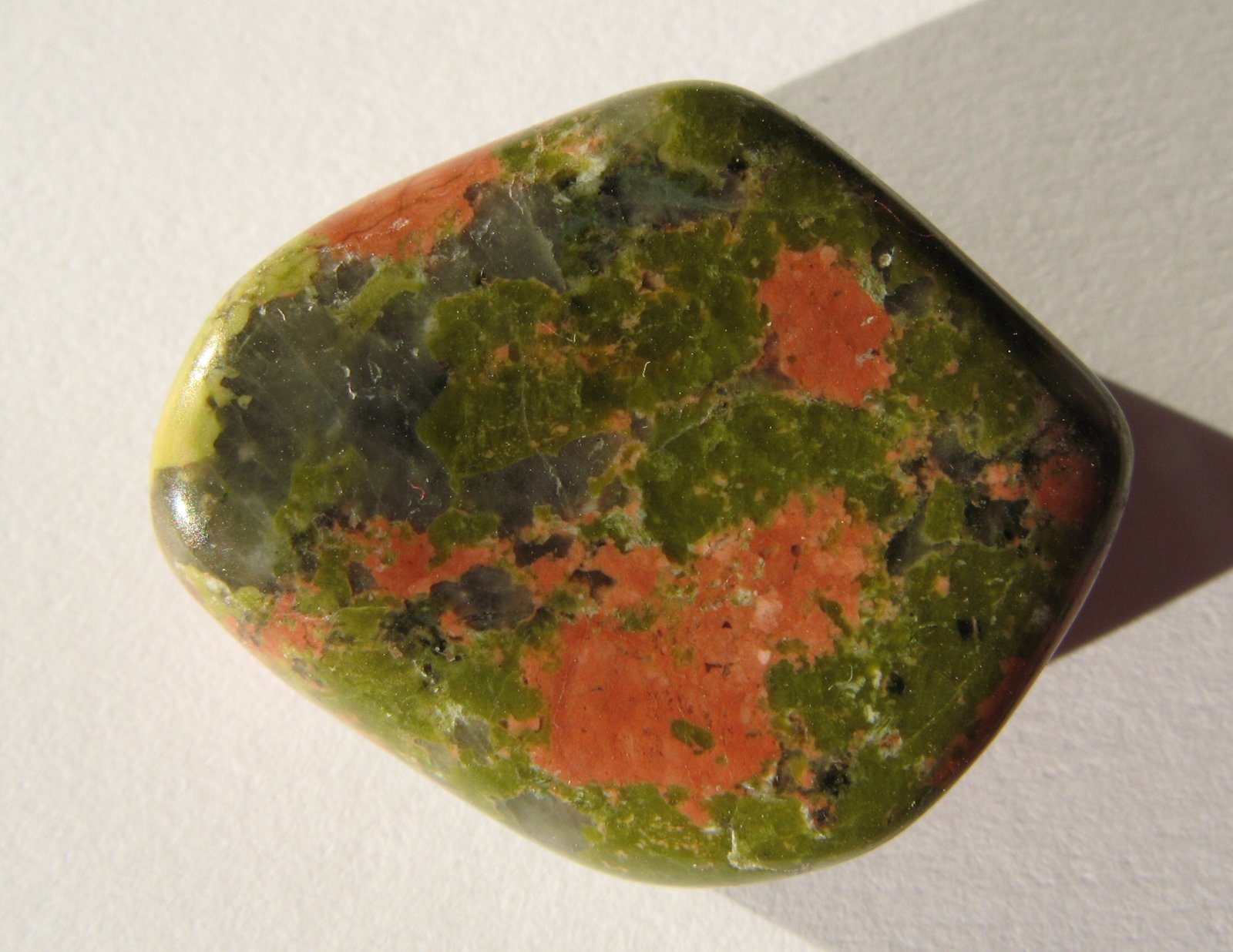 Tumble-polished unakite stone with pink feldspar and green epidote